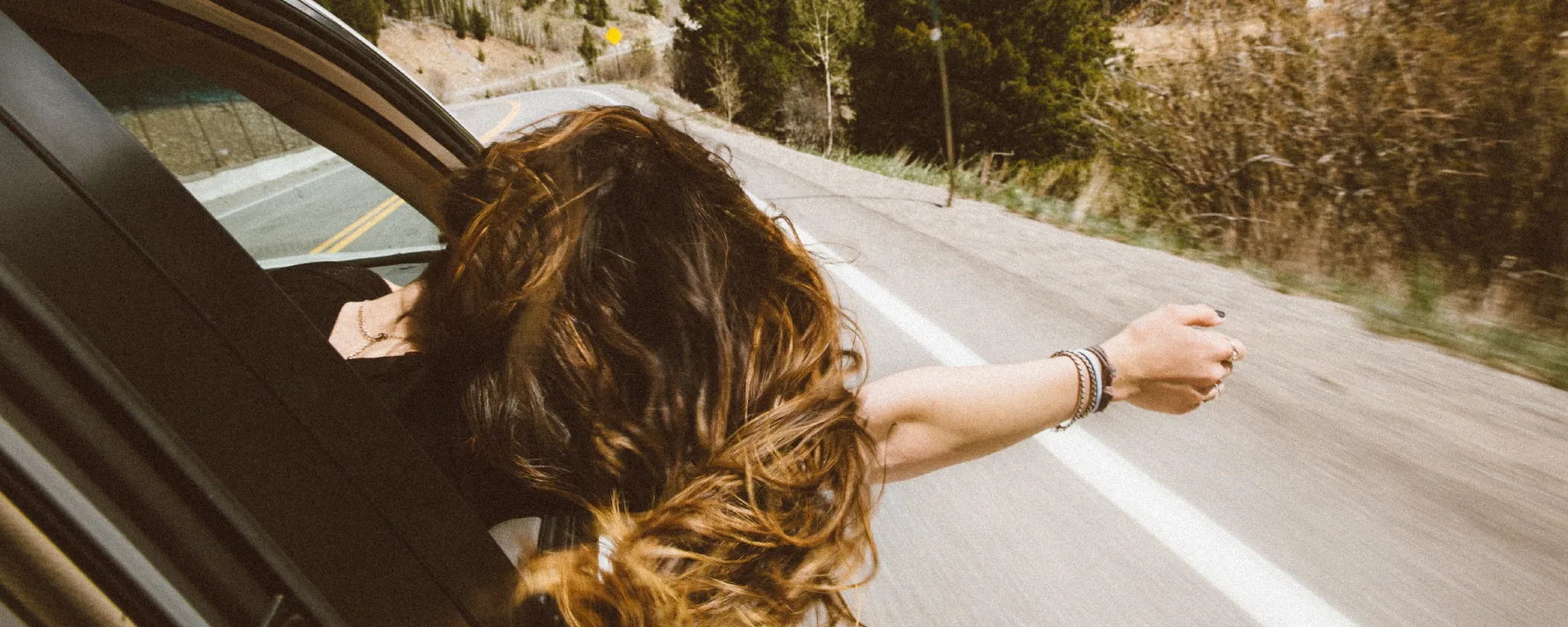 En kvinnes hår flagrer ut av bilvinduet